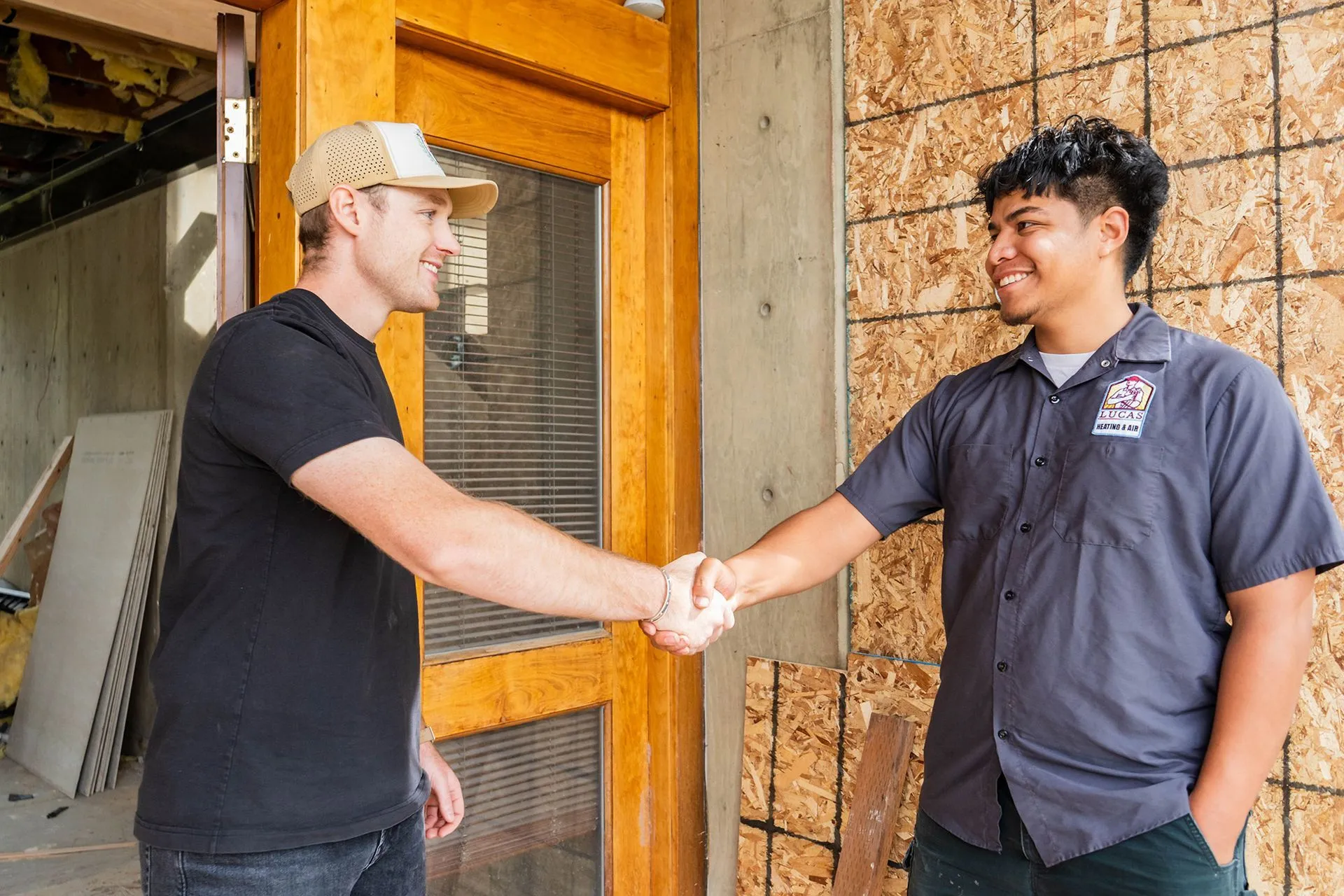Lucas Heating and Air technician in uniform shaking hands with a customer at their front door